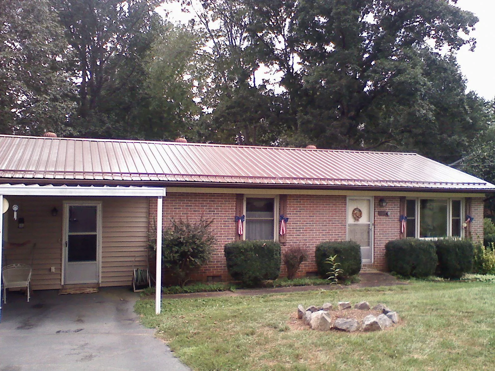Bronze metal roof and carport on a brick ranch home — Roof Repair work by our crew in Dryden